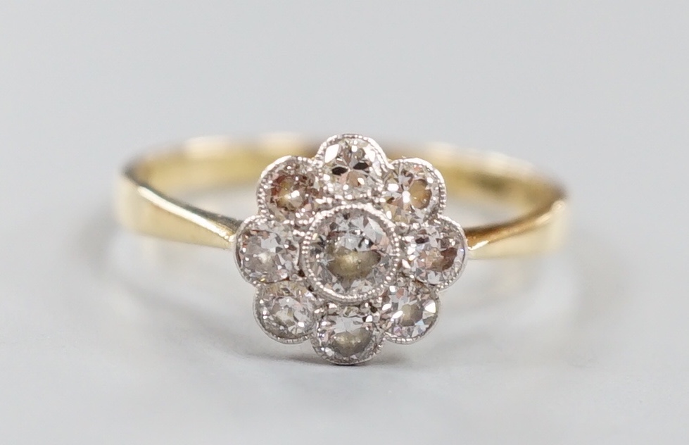 An 18ct and nine stone diamond set flower head cluster ring, size O, gross weight 2 grams.